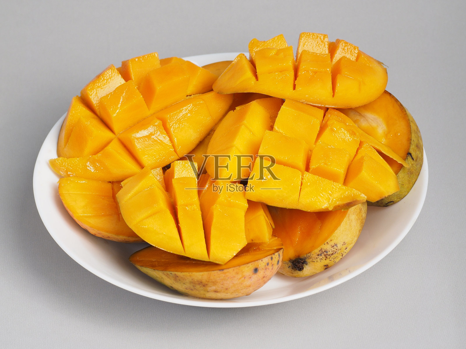 盘子里有许多切片的芒果水果。灰色的背景。照片摄影图片