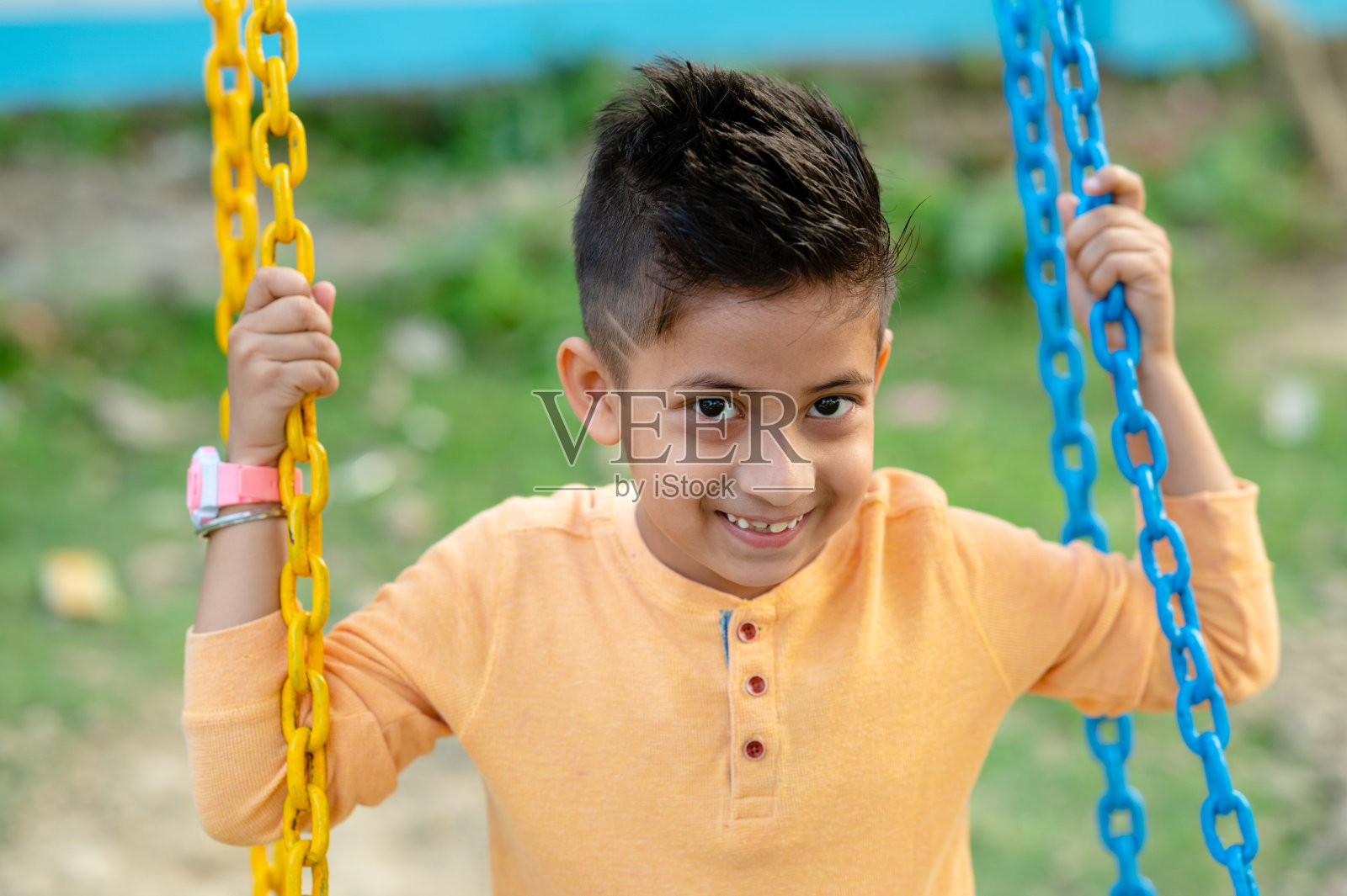小孩子在操场上玩秋千玩得很开心照片摄影图片