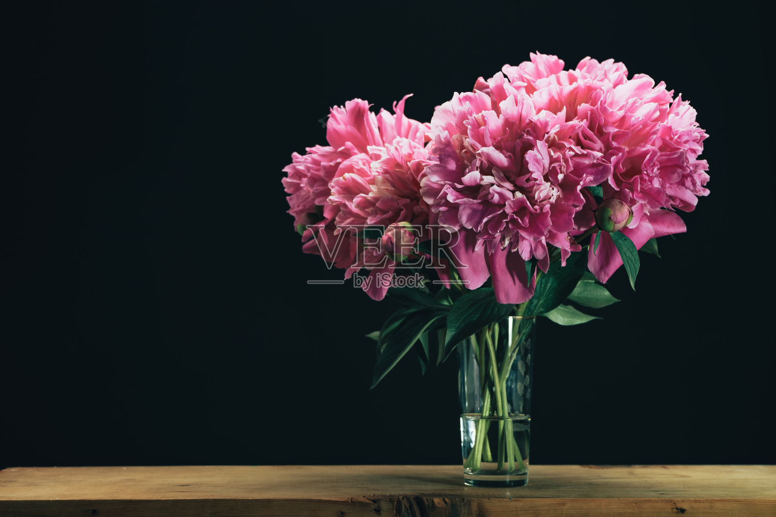 美丽的牡丹花花瓶在一个棕色的木制和黑色的背景。照片摄影图片
