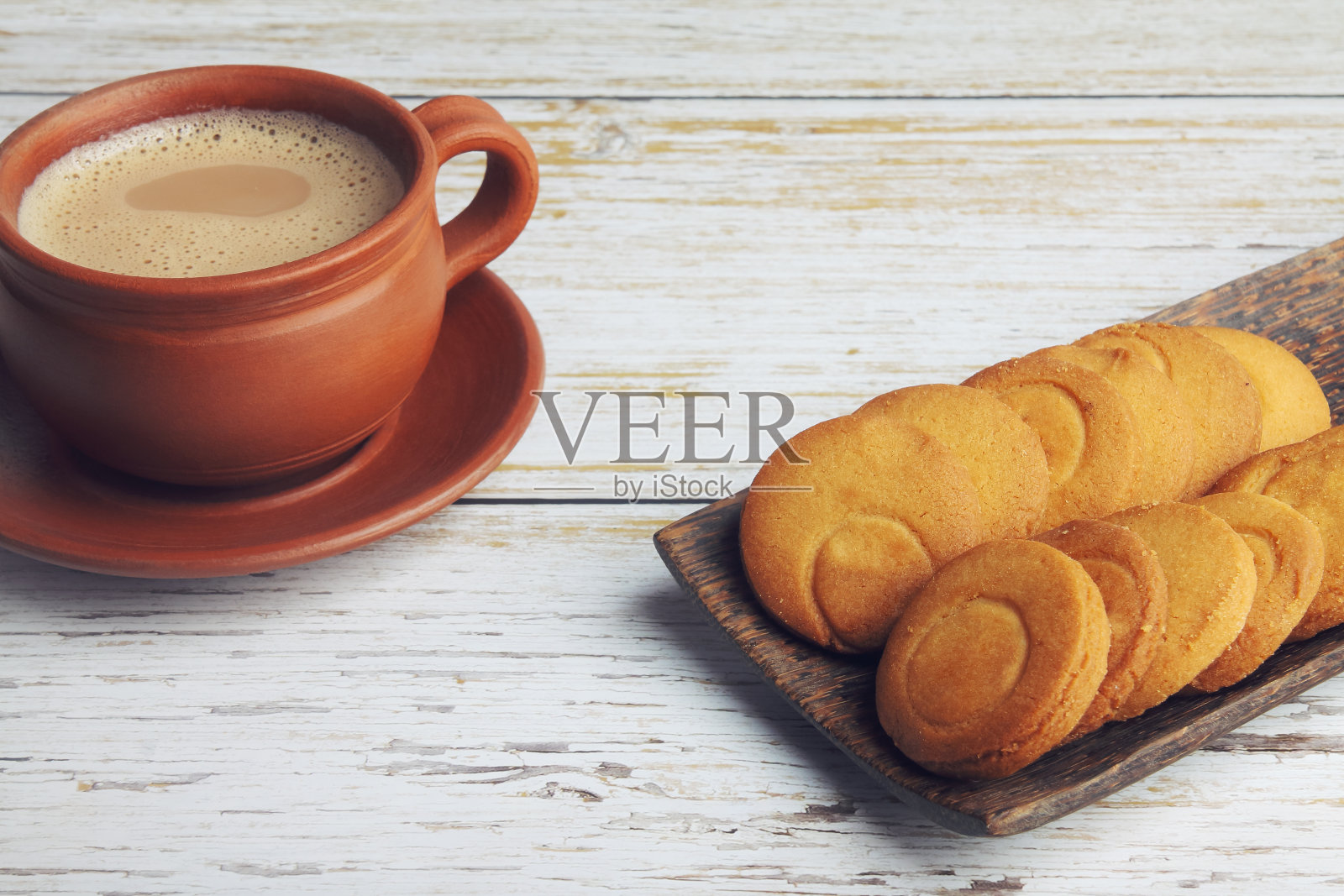 木桌上放着一杯茶和黄油饼干照片摄影图片