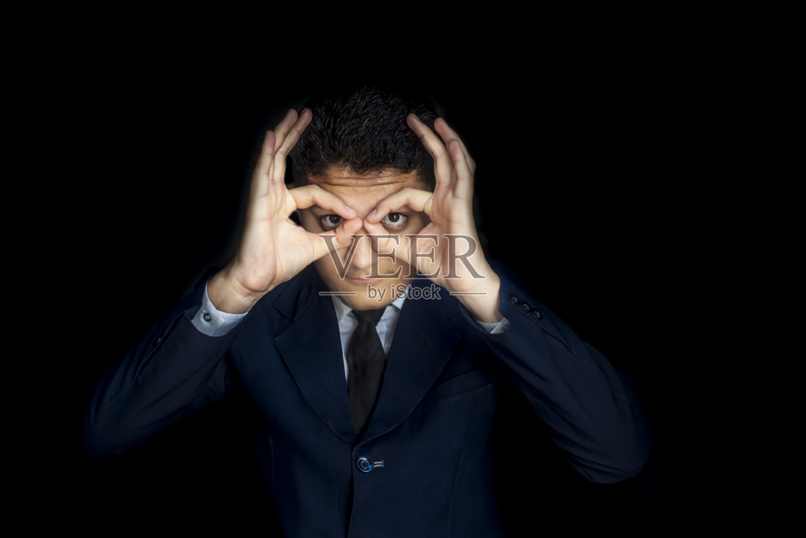 沮丧的人做了一副眼镜,给了一个幽默的猫头鹰表情孤立在黑色的背景。西装革履的男人做出幽默的手势。照片摄影图片