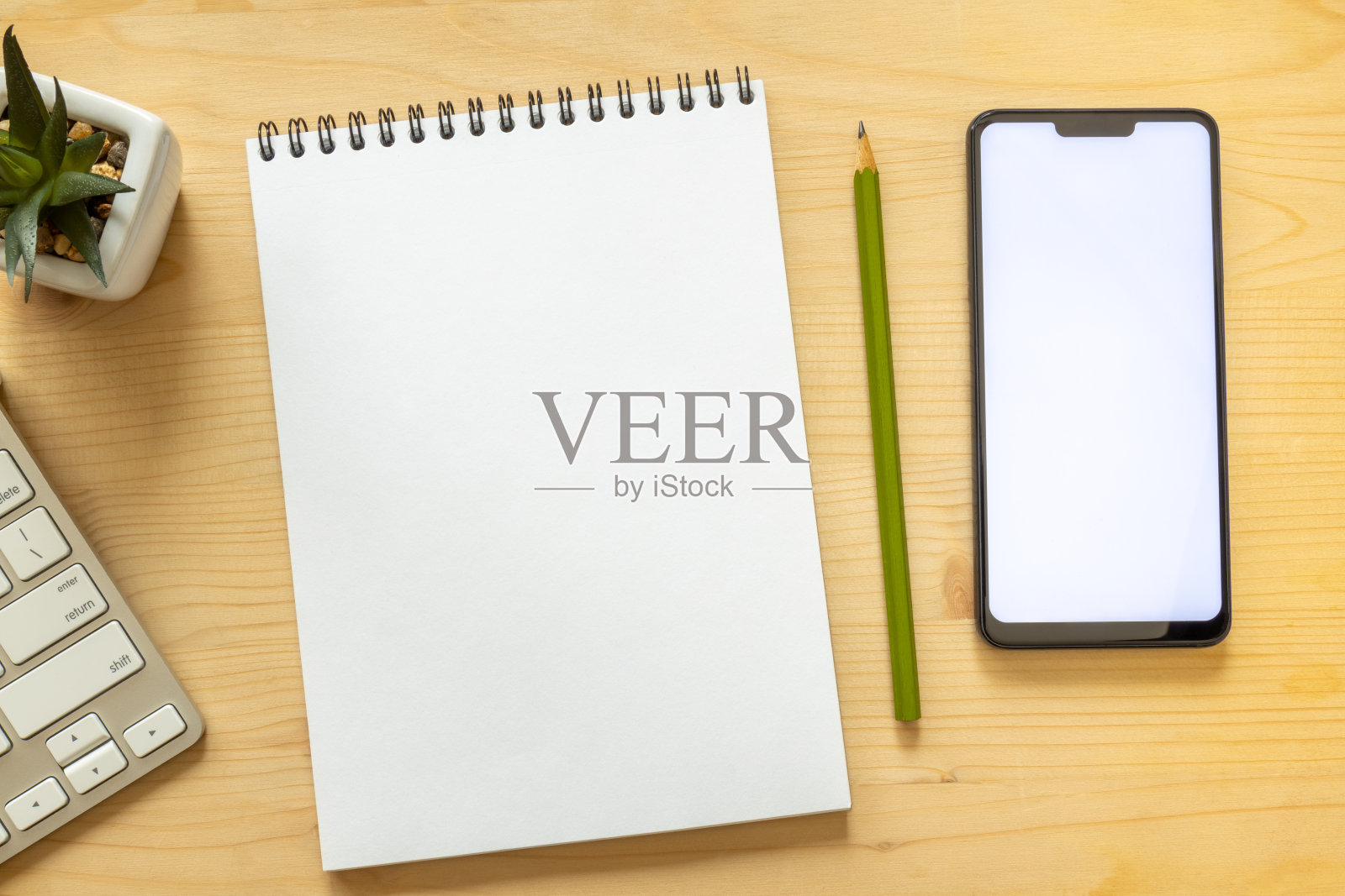 静物模拟与智能手机,记事本,铅笔和电脑键盘在一个轻木桌。照片摄影图片