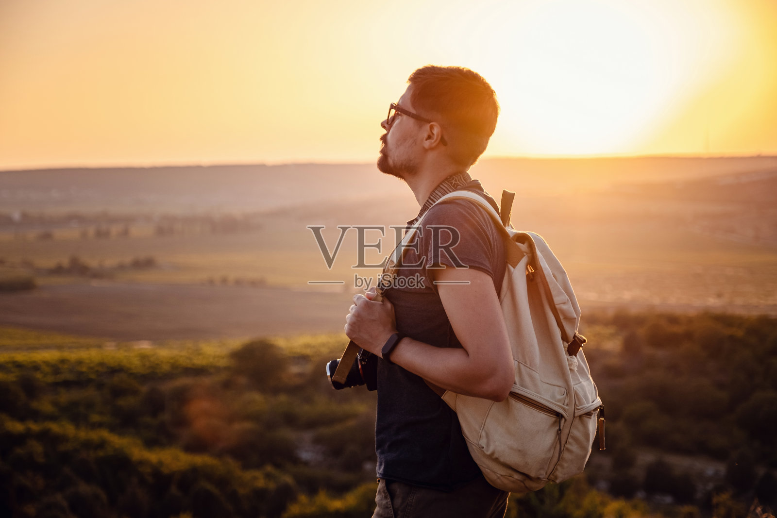 夕阳西下时,一个人站在山上。照片摄影图片