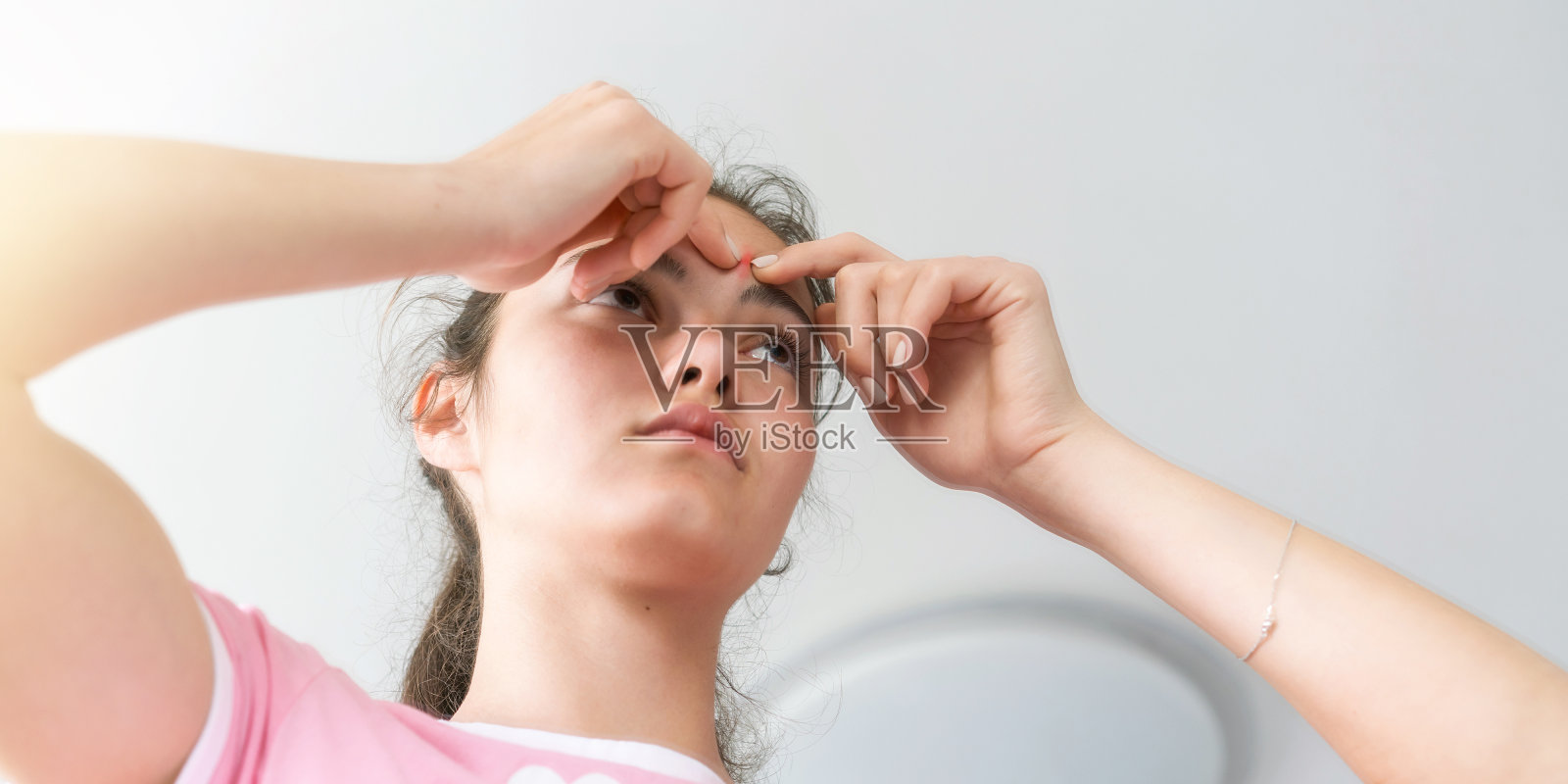 少女扎着马尾辫,额头上长着青春痘照片摄影图片