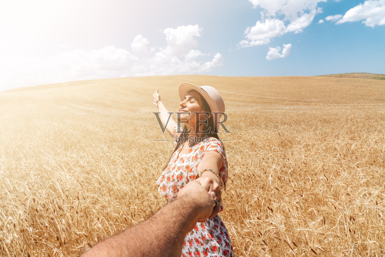 美丽的女人牵手在一个农业领域与蓝天和云彩的背景。浪漫和乡村概念。照片摄影图片