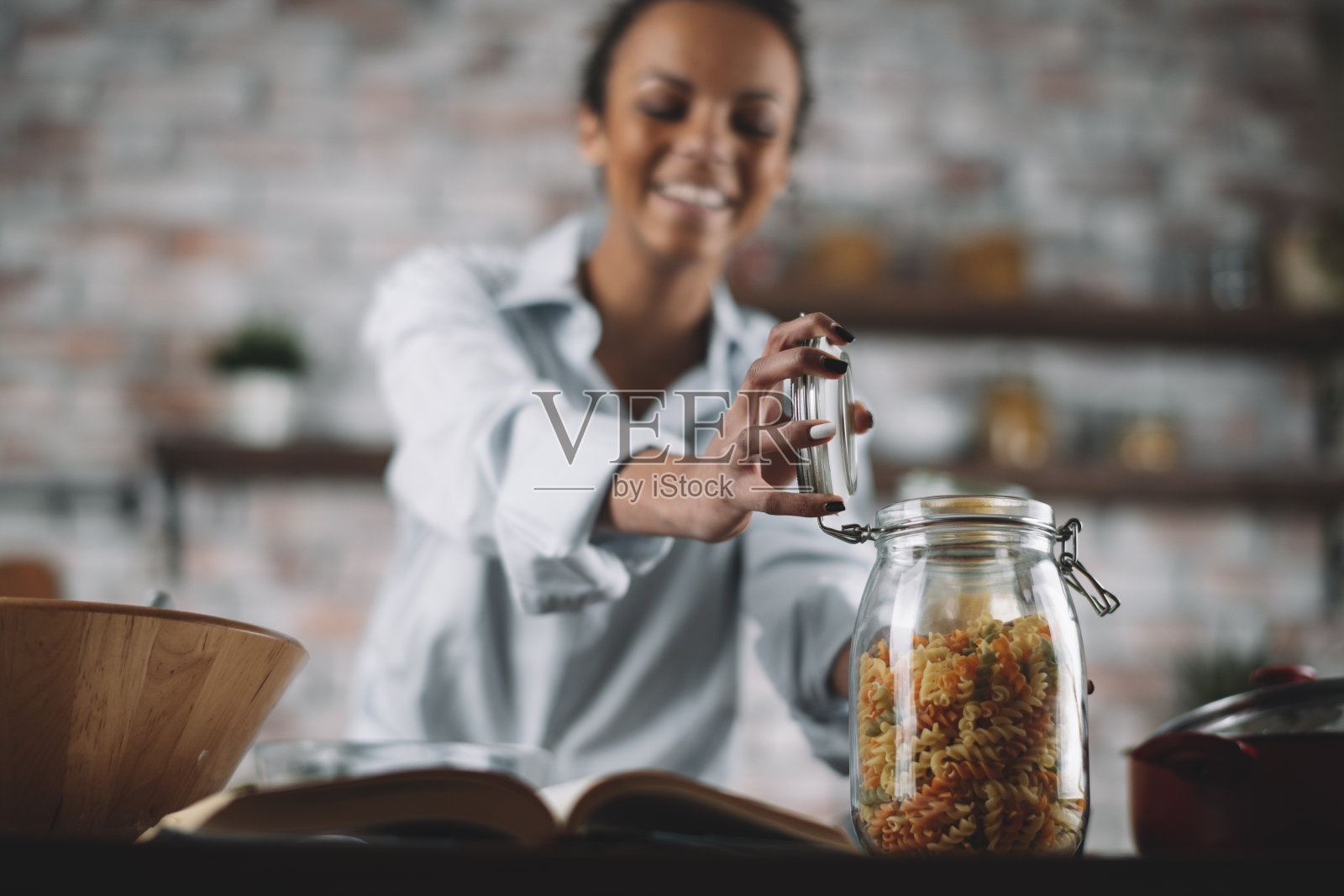 漂亮女人在家里做饭的时候玩得很开心。照片摄影图片