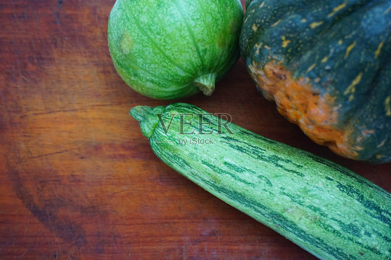 整只绿色的圆鞋,紧挨着cabutia鞋和一只西葫芦,放在木板上,照片摄影图片