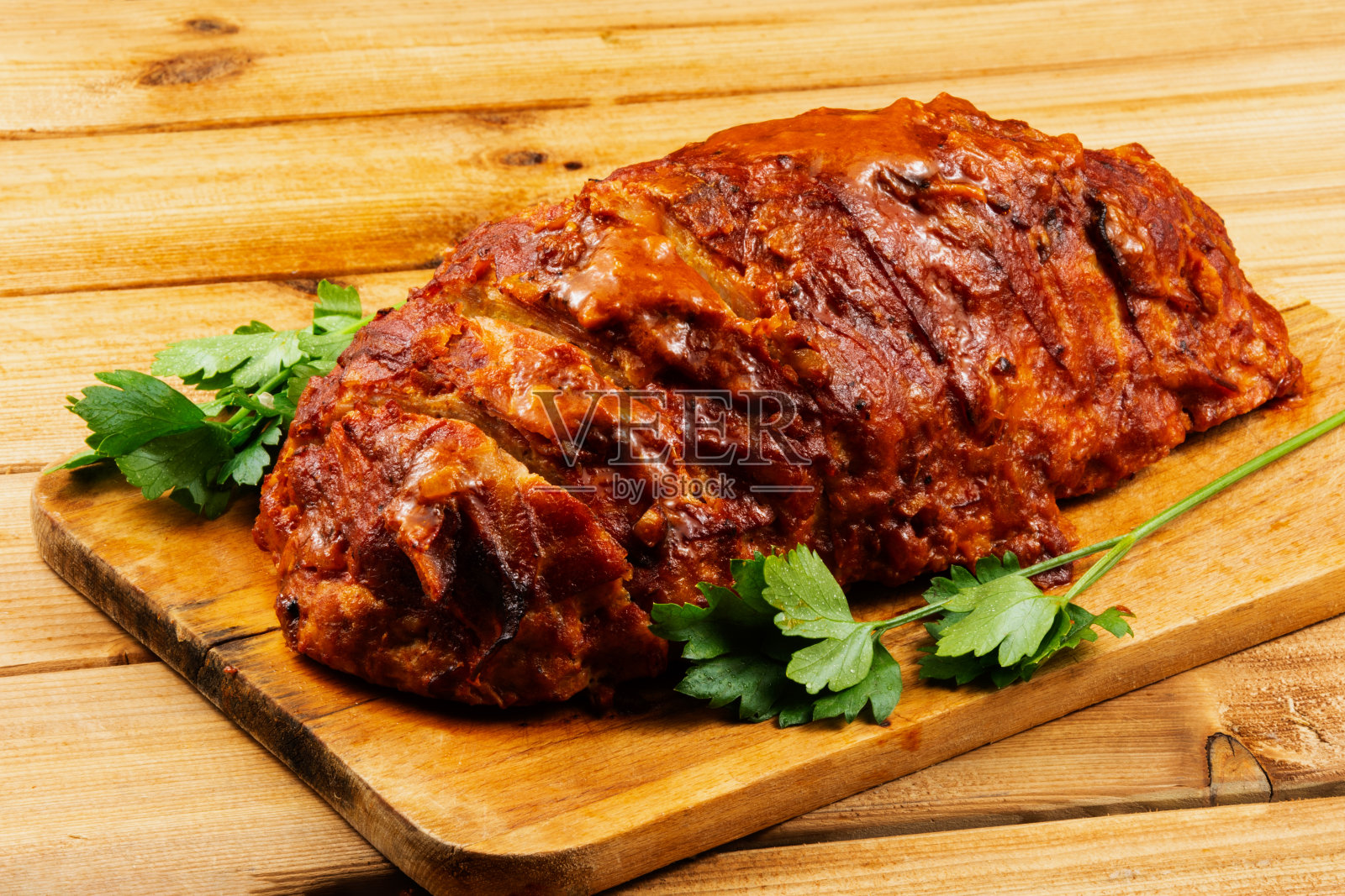 木制背景的切菜板上的经典烘肉卷。背景是红色和黄色的圣女果,欧芹,小麦穗照片摄影图片