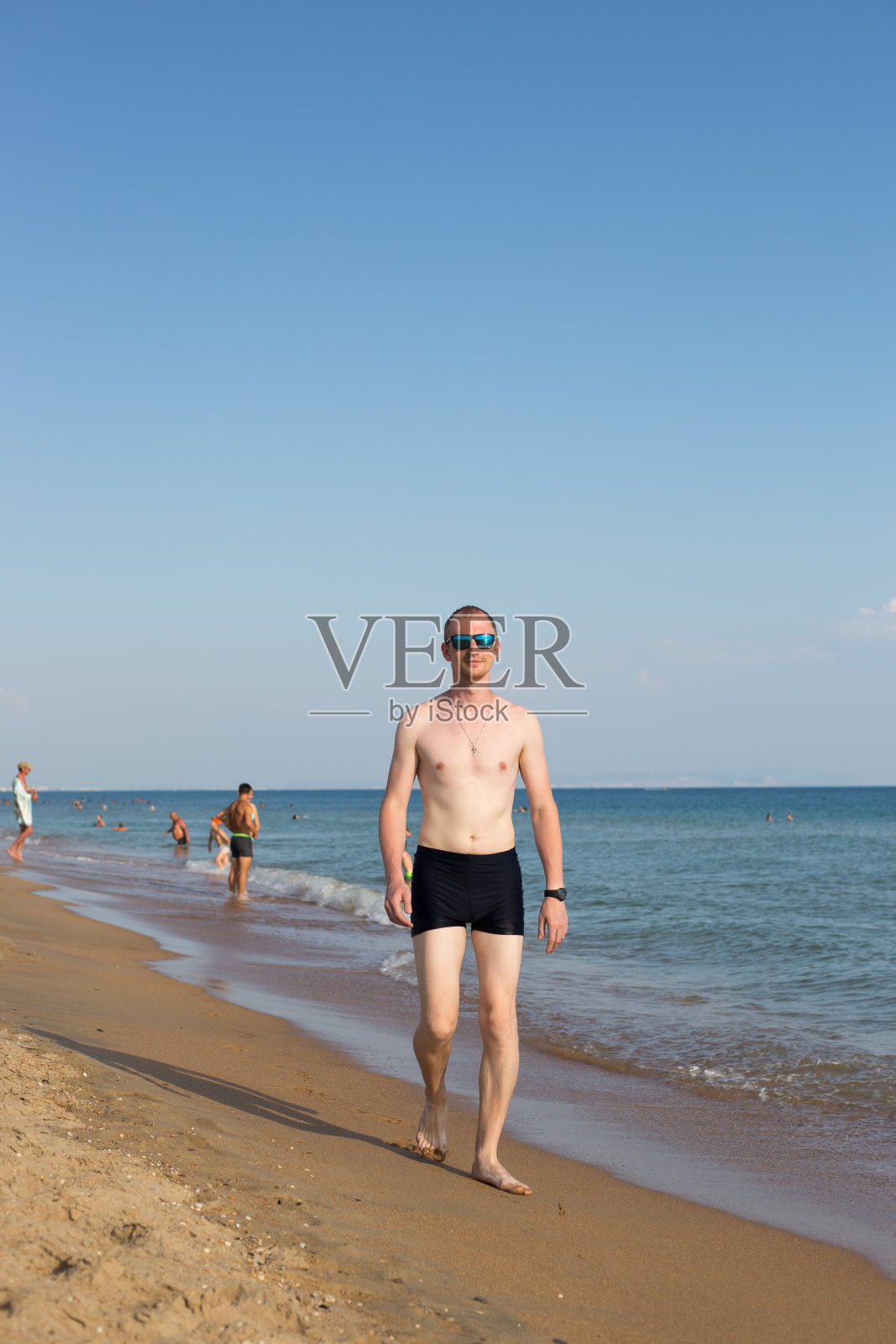 穿着沙滩短裤的年轻人沿着海滨散步照片摄影图片