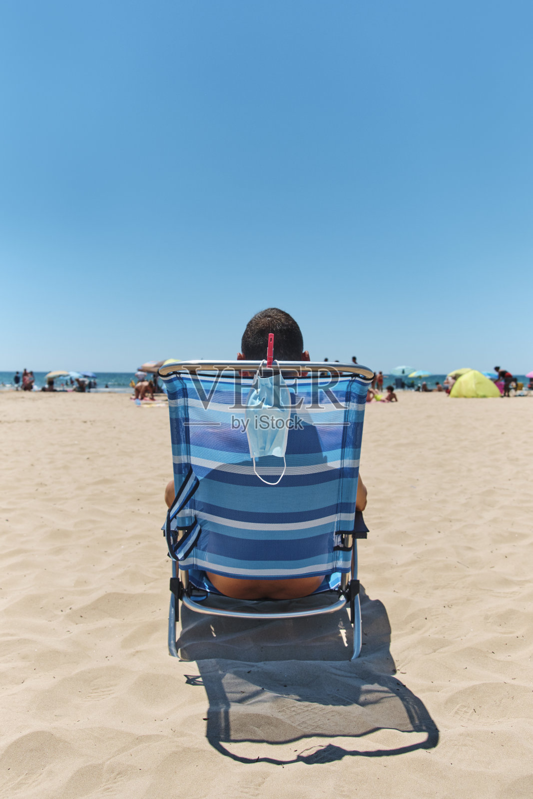 面具和男人坐在沙滩上的躺椅上照片摄影图片