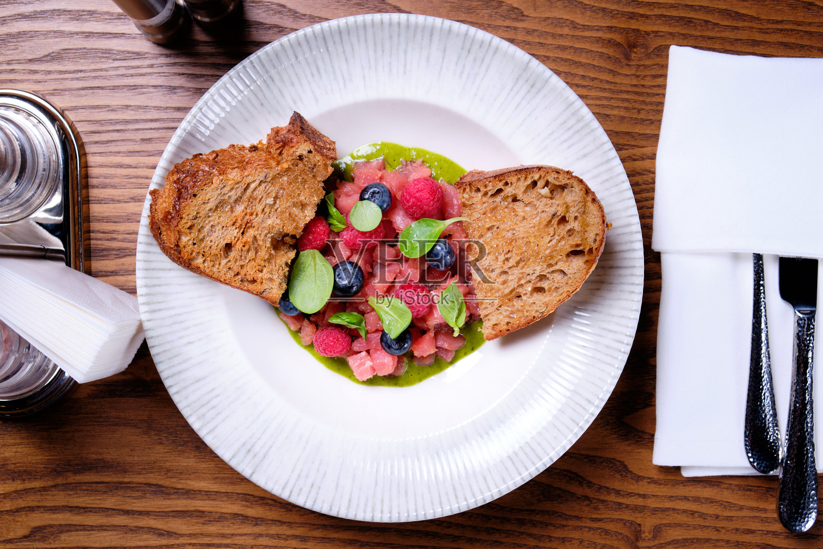 金枪鱼鞑靼与覆盆子和蓝莓在一个白色的盘子。照片摄影图片