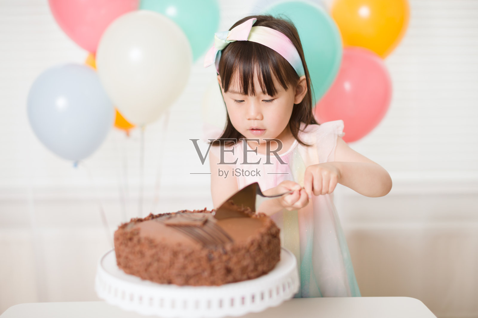 蹒跚学步的女孩切生日蛋糕庆祝她的四岁生日照片摄影图片