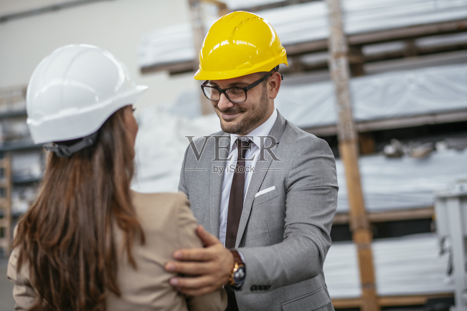 商人和女商人在工厂握手。照片摄影图片
