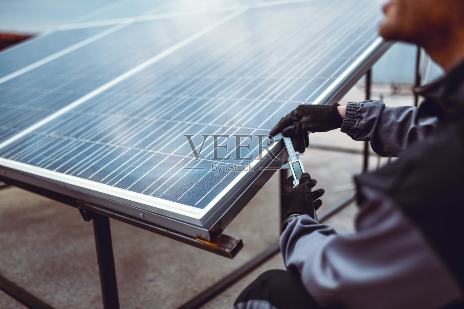 工人在屋顶安装太阳能板时测量其厚度照片摄影图片