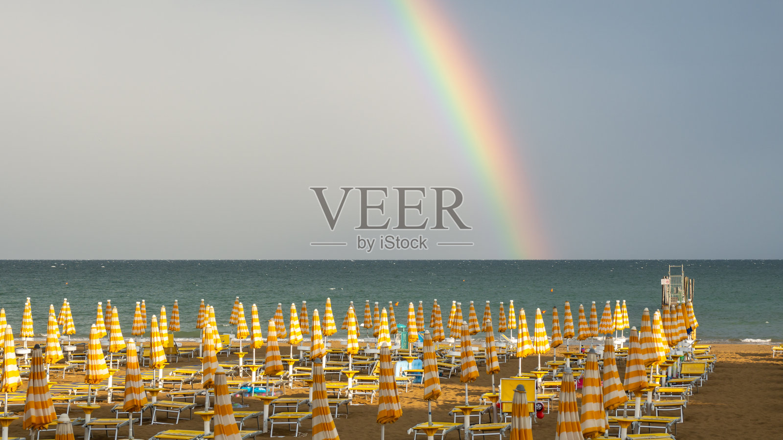 亚得里亚海上的美丽彩虹。彩虹的鲜艳颜色和绿色的大海形成了鲜明的对比。前景是杰索洛海滩。沙滩上没有人。神奇的大自然照片摄影图片