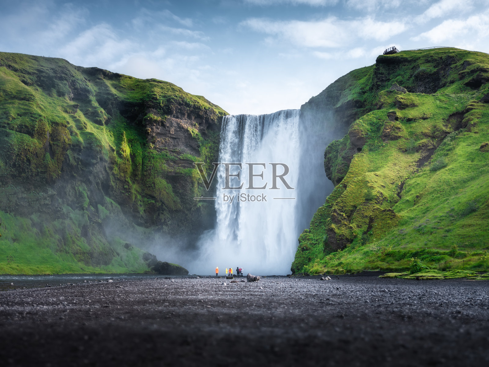 Skogafoss瀑布,冰岛。山谷和晴朗的天空。夏季自然景观。冰岛的自然。一群人在大瀑布附近。旅游形象照片摄影图片
