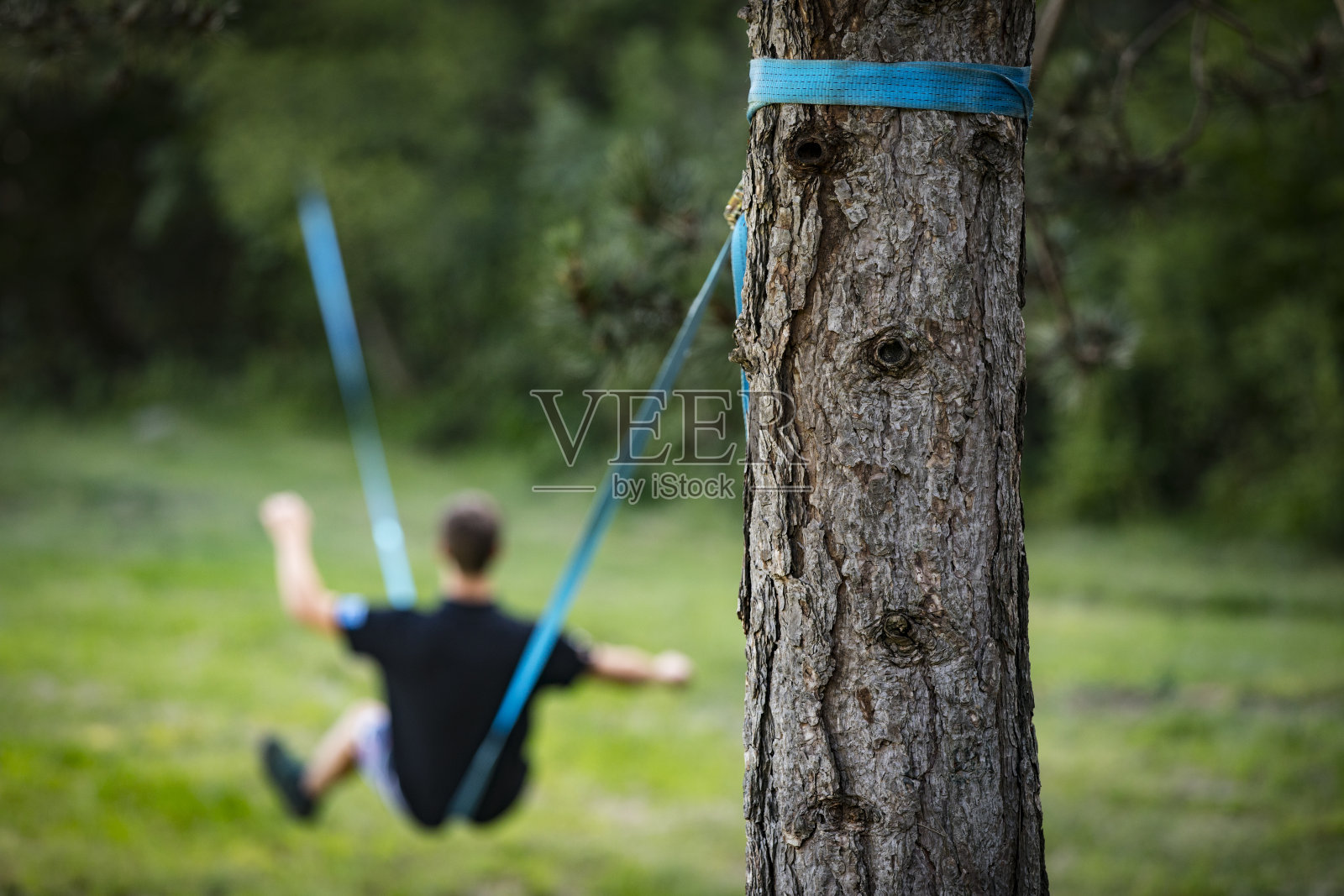一个陌生的年轻人坐在松弛的绳索上保持平衡照片摄影图片