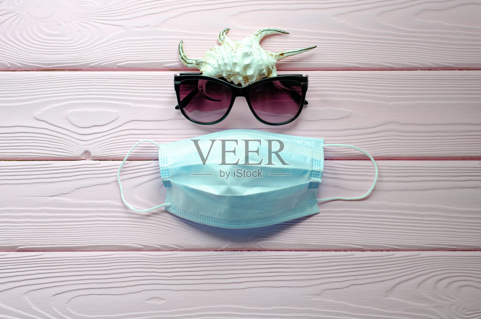 贝壳,太阳镜和防护面具在一个粉红色的木制背景。2020年夏季和假期防病毒。旅行的概念。照片摄影图片