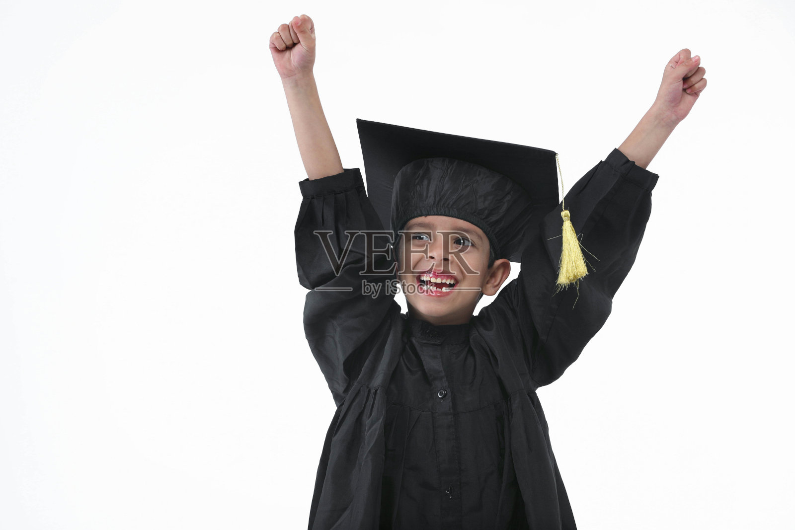 小学男孩戴着毕业帽和毕业服,手拿学位站在那里微笑照片摄影图片