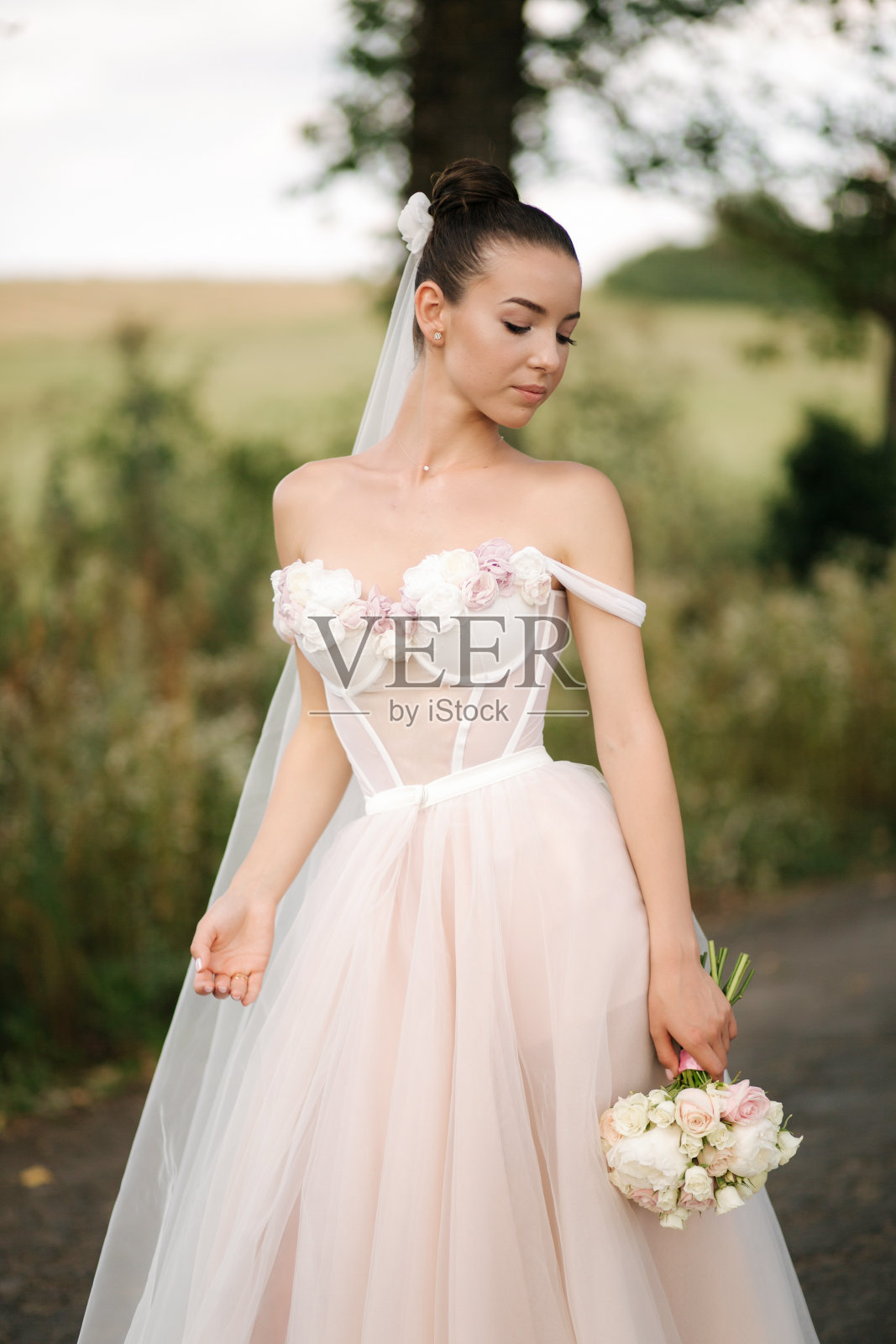 华丽的新娘在优雅的婚纱站在林登巷与捧花和摆姿势的摄影师照片摄影图片