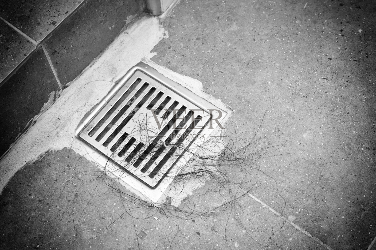 洗手间洗浴后头发脱落堵塞排水管。癌症化疗患者的脱发或症状。黑白色调照片摄影图片