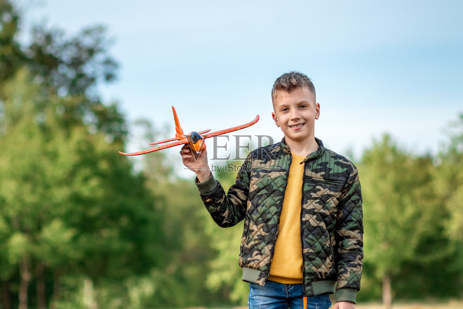 男孩在绿色的背景下放飞玩具飞机。梦想的概念,职业的选择,飞行员,童年。副本的空间。照片摄影图片