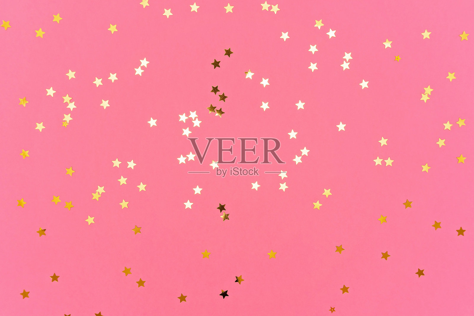 金色的星星在粉红色的时尚背景上闪闪发光。照片摄影图片