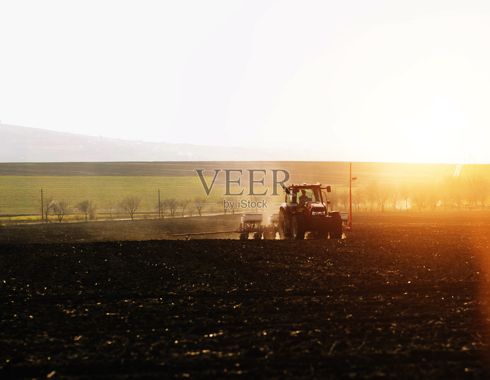 农民在春天日落时用拖拉机在农田里播种庄稼照片摄影图片