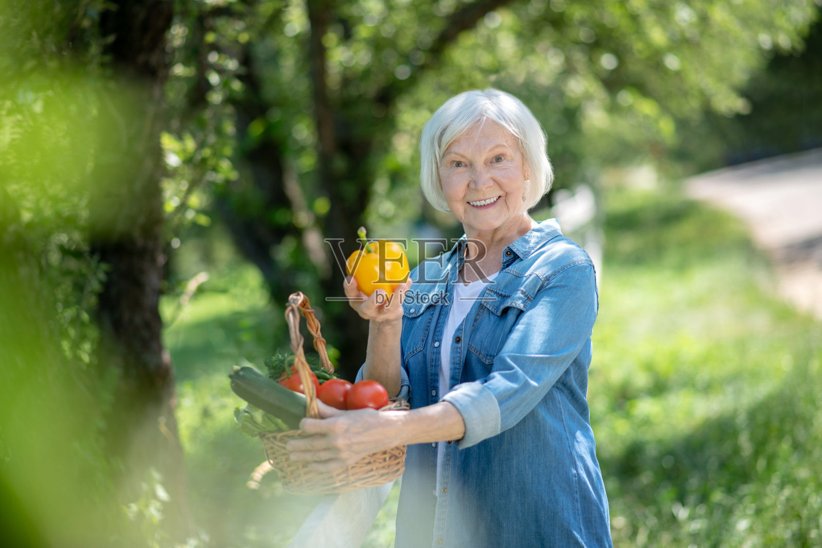 快乐的老妇人拿着黄色的甜椒照片摄影图片