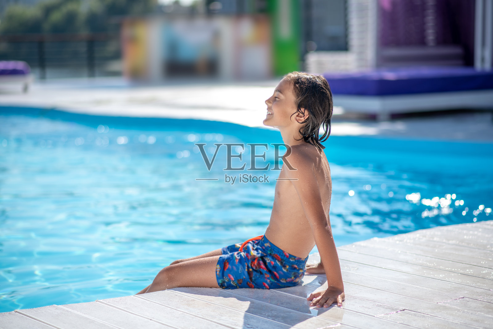 男孩坐在泳池边晒太阳照片摄影图片