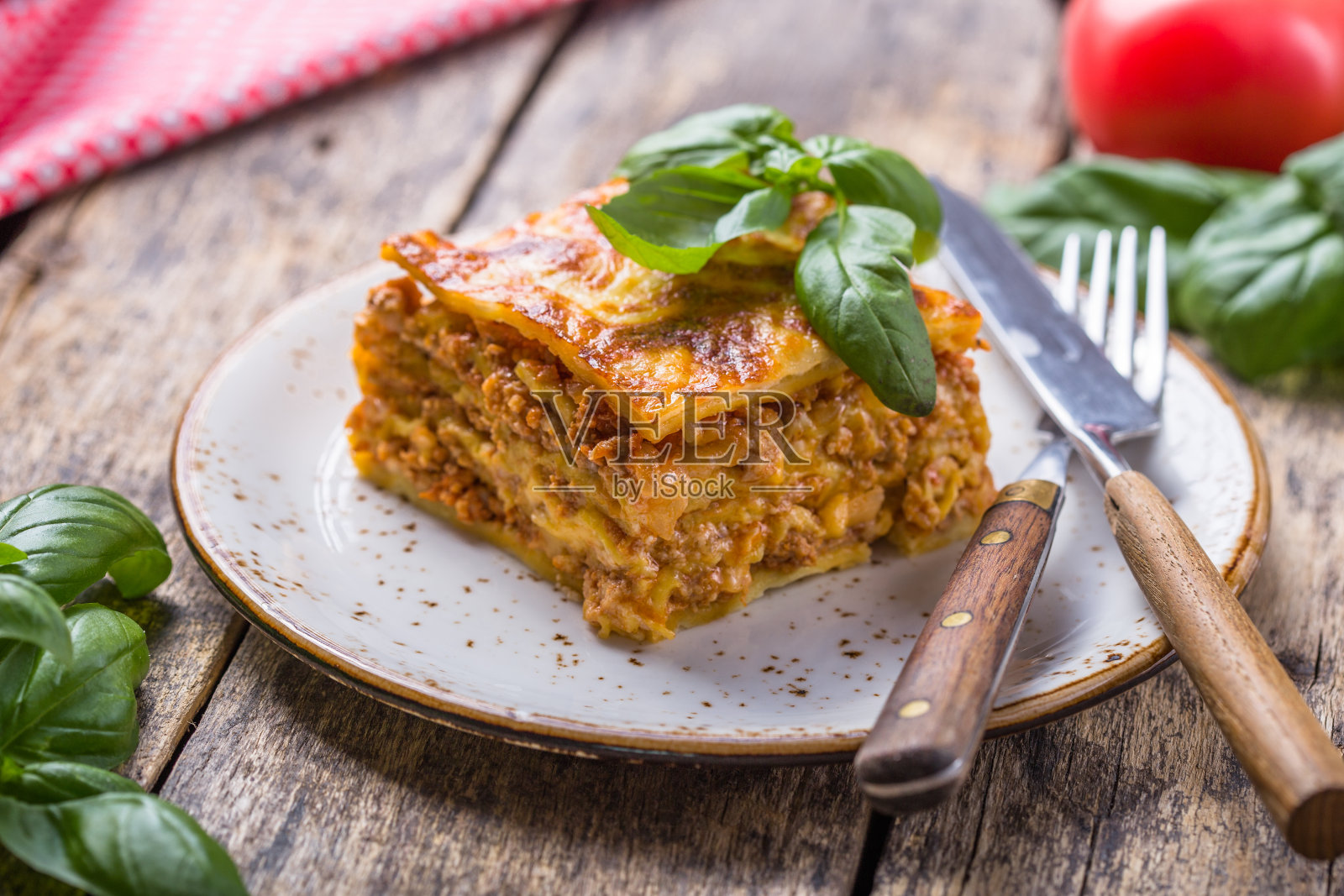 木桌上盛有新鲜罗勒和帕尔马干酪的肉千层面。关闭了。意大利菜。照片摄影图片