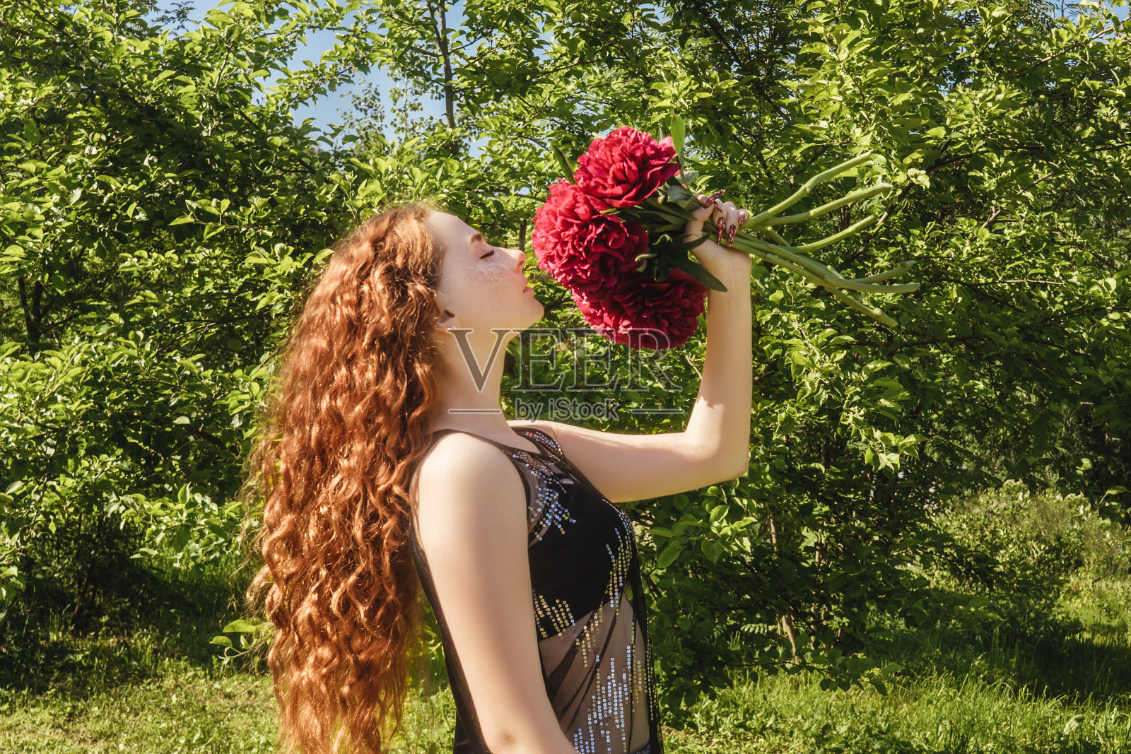 年轻美丽的姑娘手里拿着牡丹。照片摄影图片