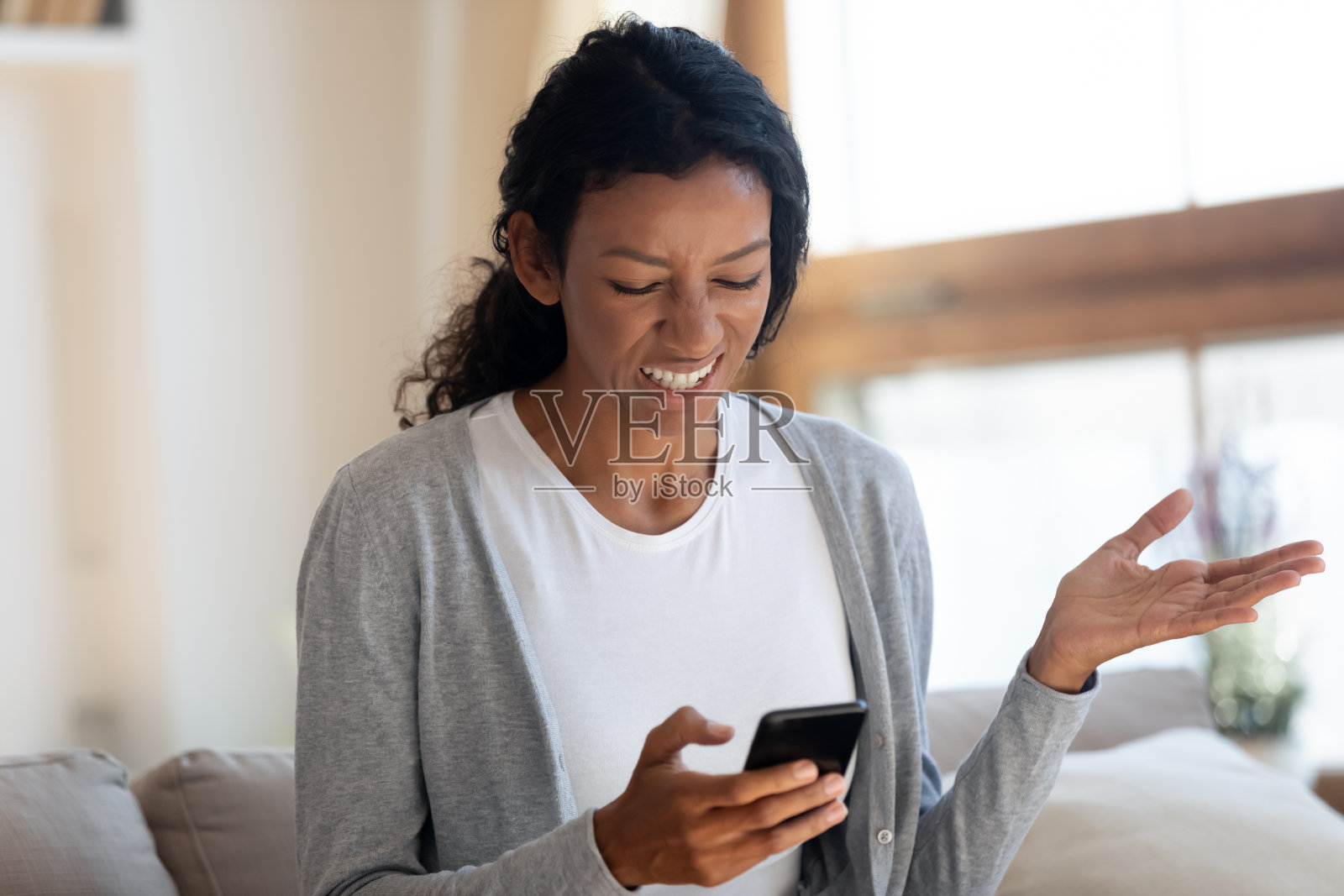 愤怒的非洲女孩看着智能手机屏幕照片摄影图片