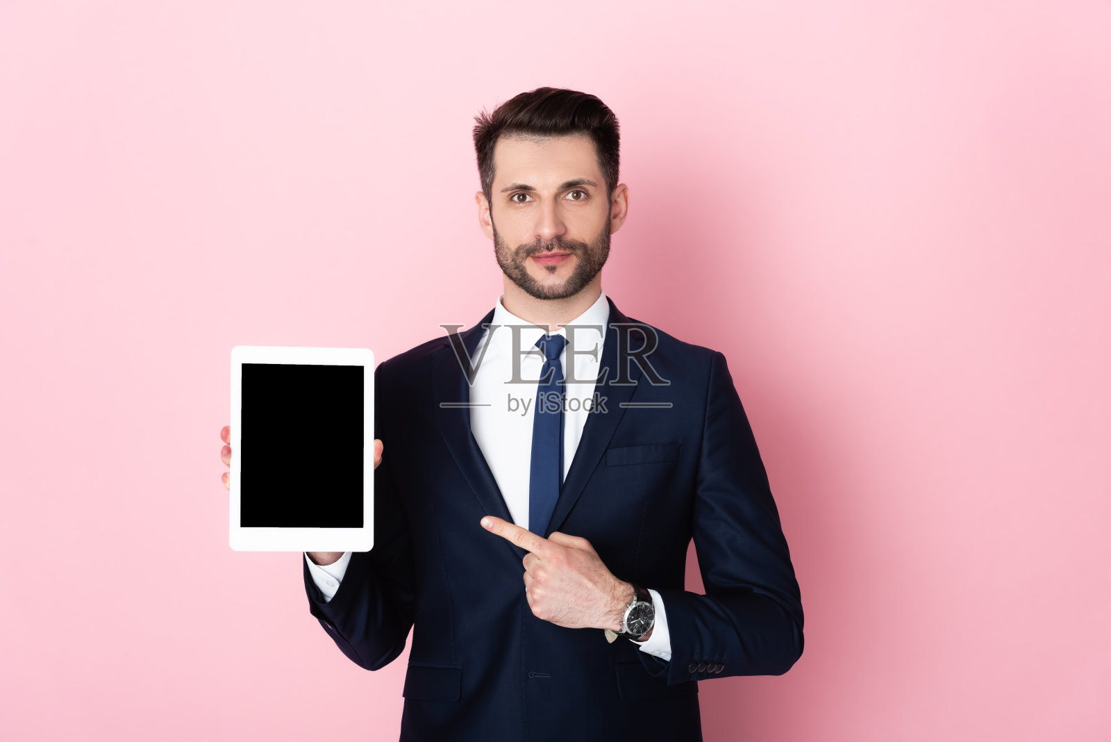 英俊的商人用手指指着粉红色空白屏幕的数字平板电脑照片摄影图片