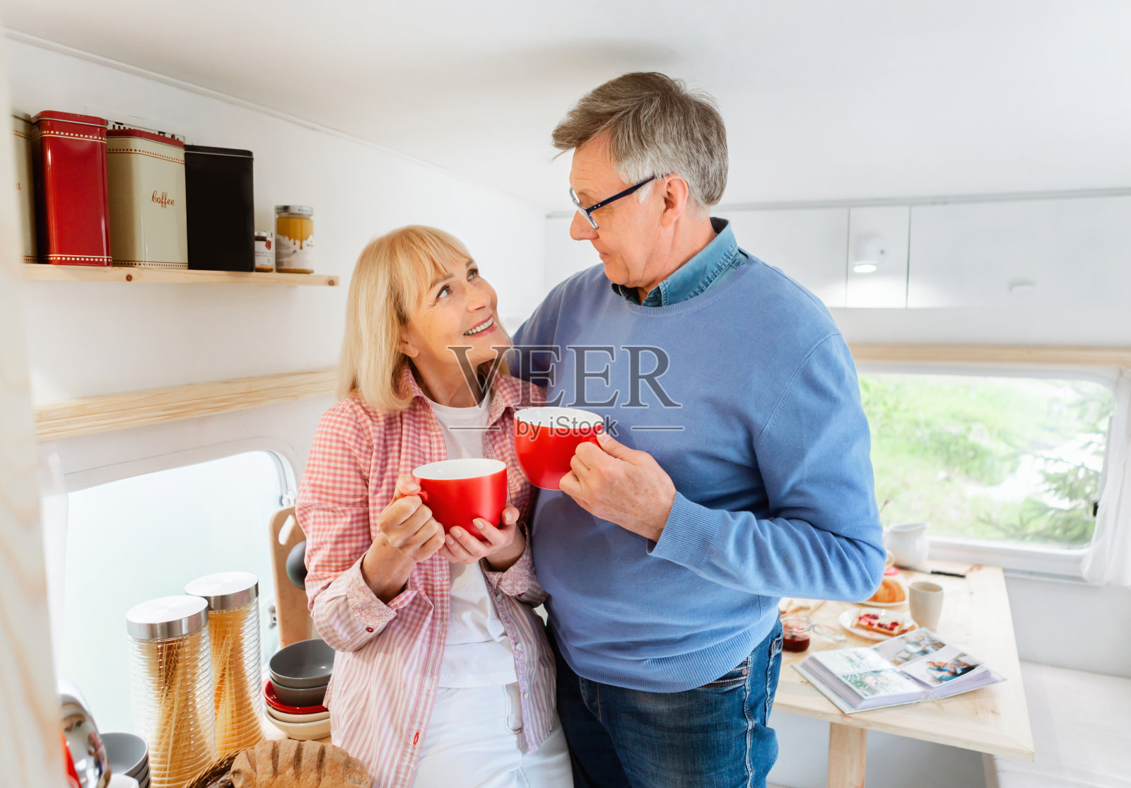 一对快乐的新婚夫妇在野营旅行的拖车里拥抱和喝咖啡照片摄影图片