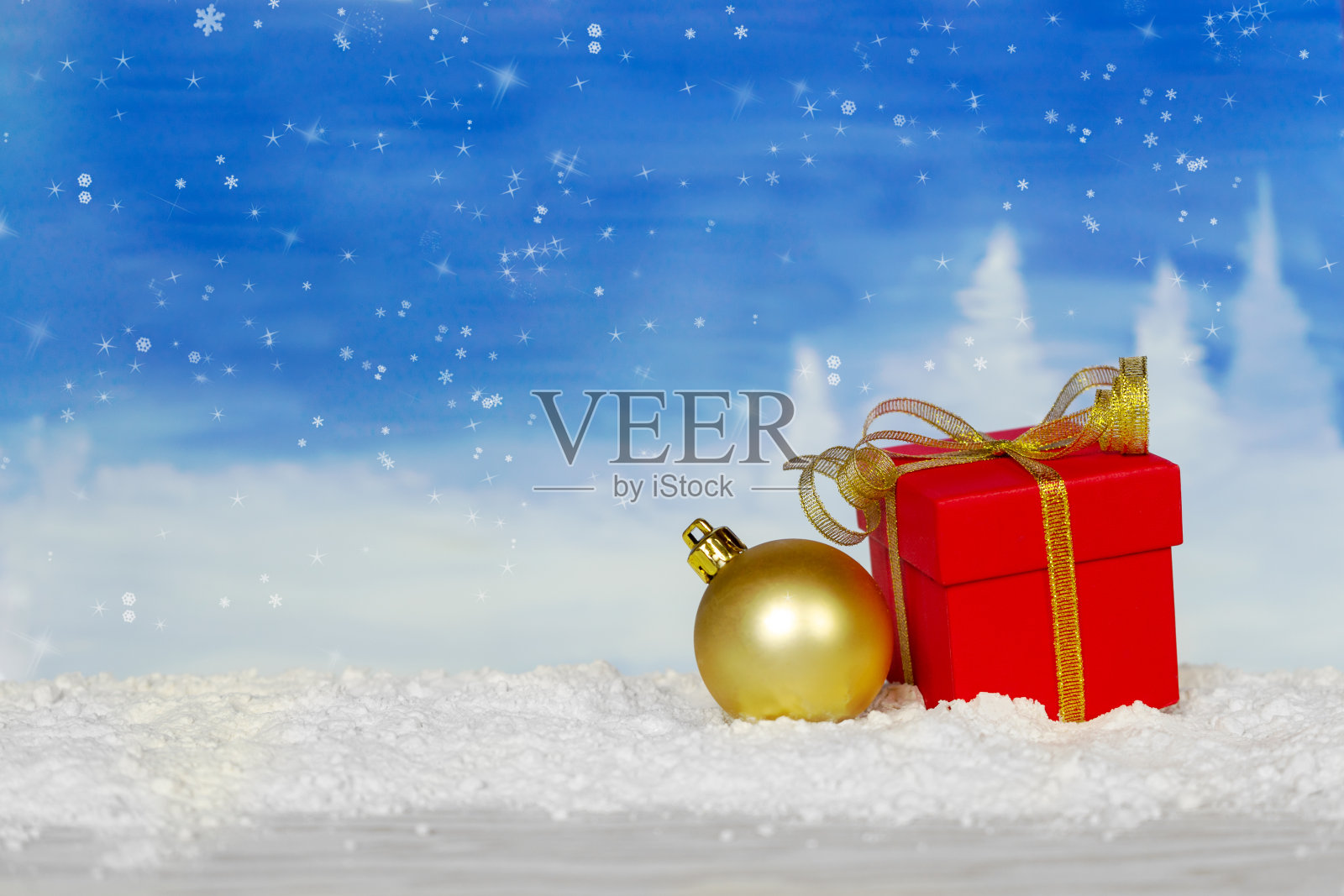 红色礼盒与金色丝带和圣诞球在一个蓝色的雪背景。圣诞贺卡与文字的地方。照片摄影图片