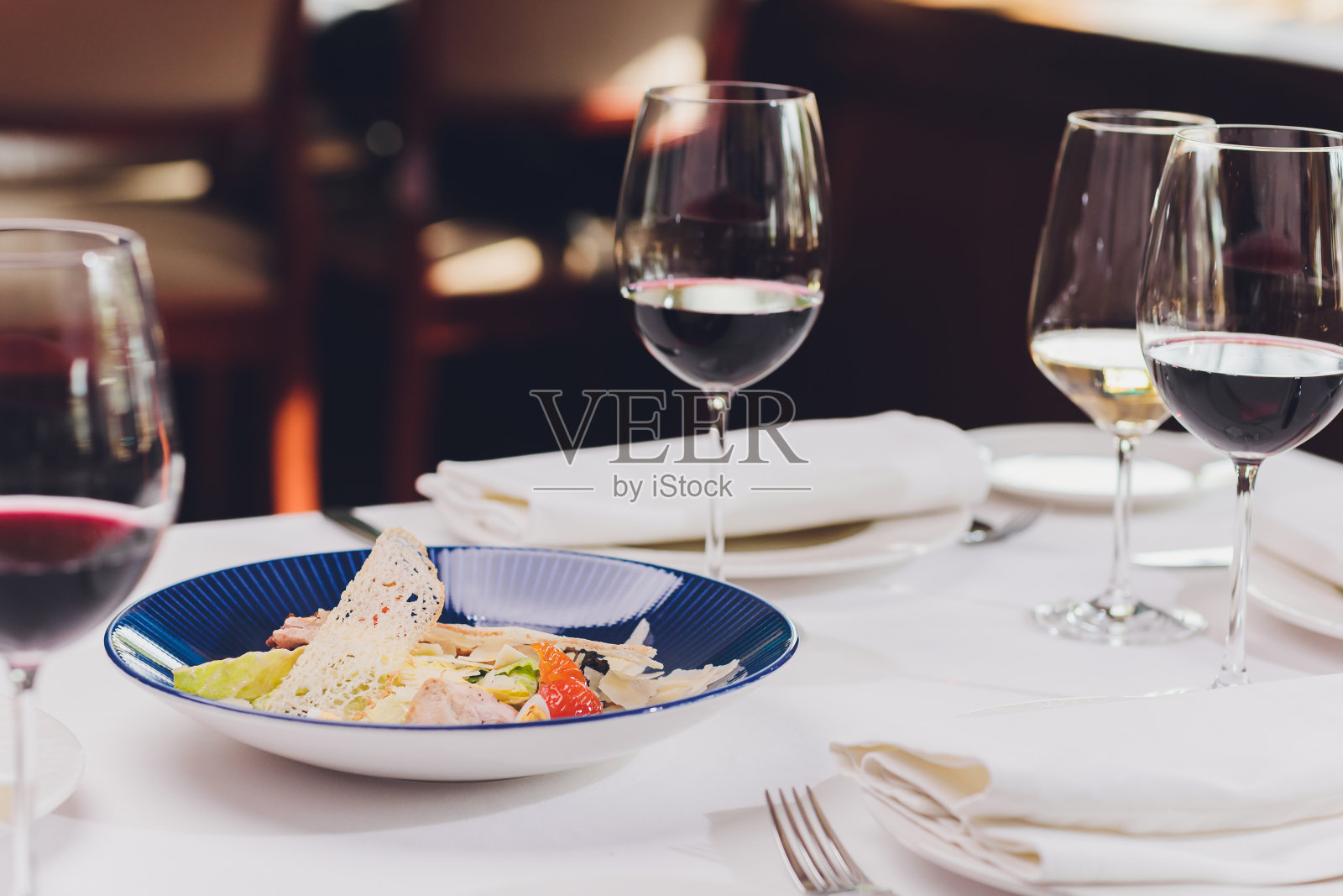 以乡村为背景的蓝色盘子上的鸡肉凯撒沙拉。照片摄影图片