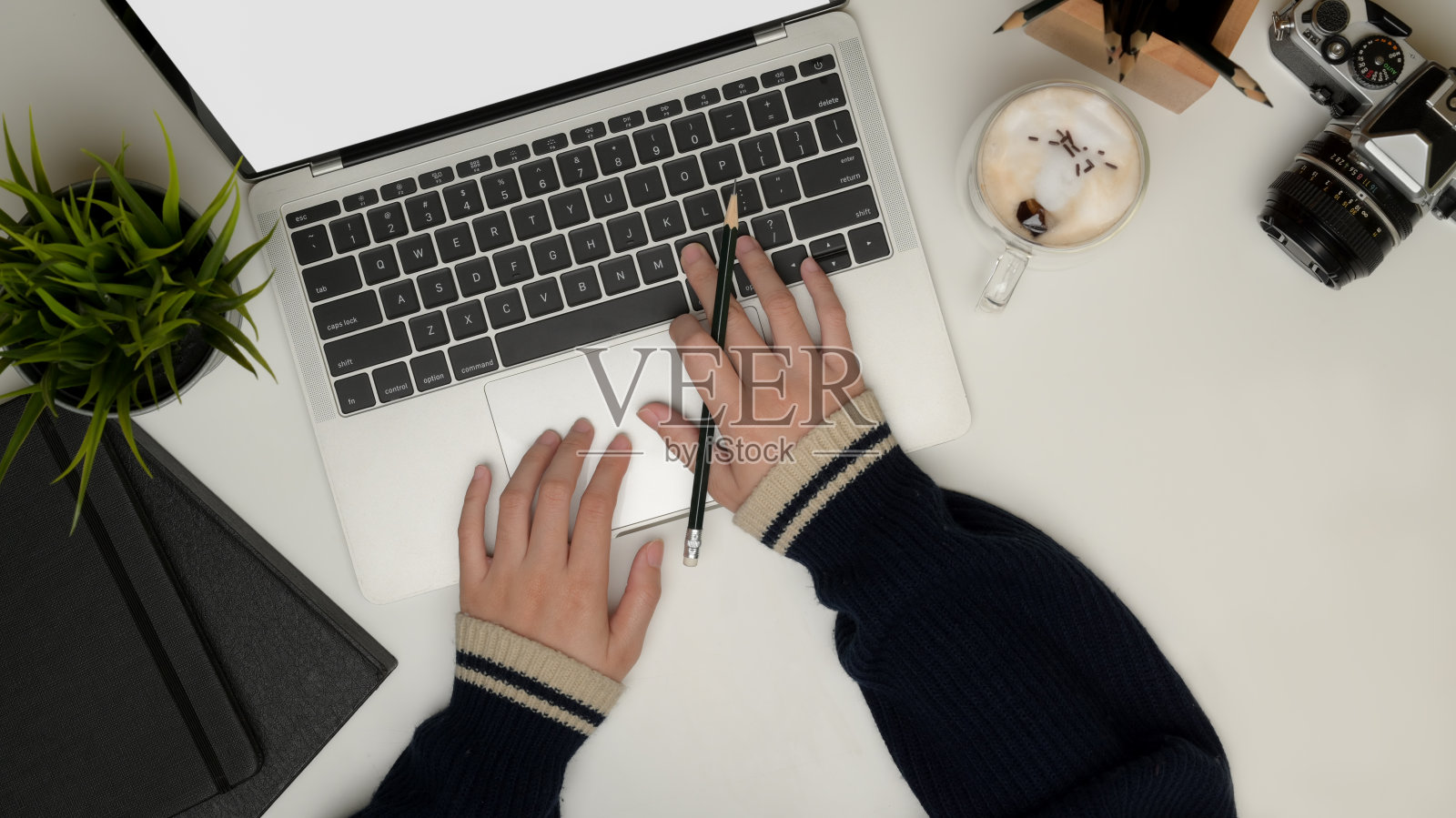 女性在办公桌上使用笔记本电脑,配有相机、文具、咖啡杯和装饰品,剪切路径。照片摄影图片