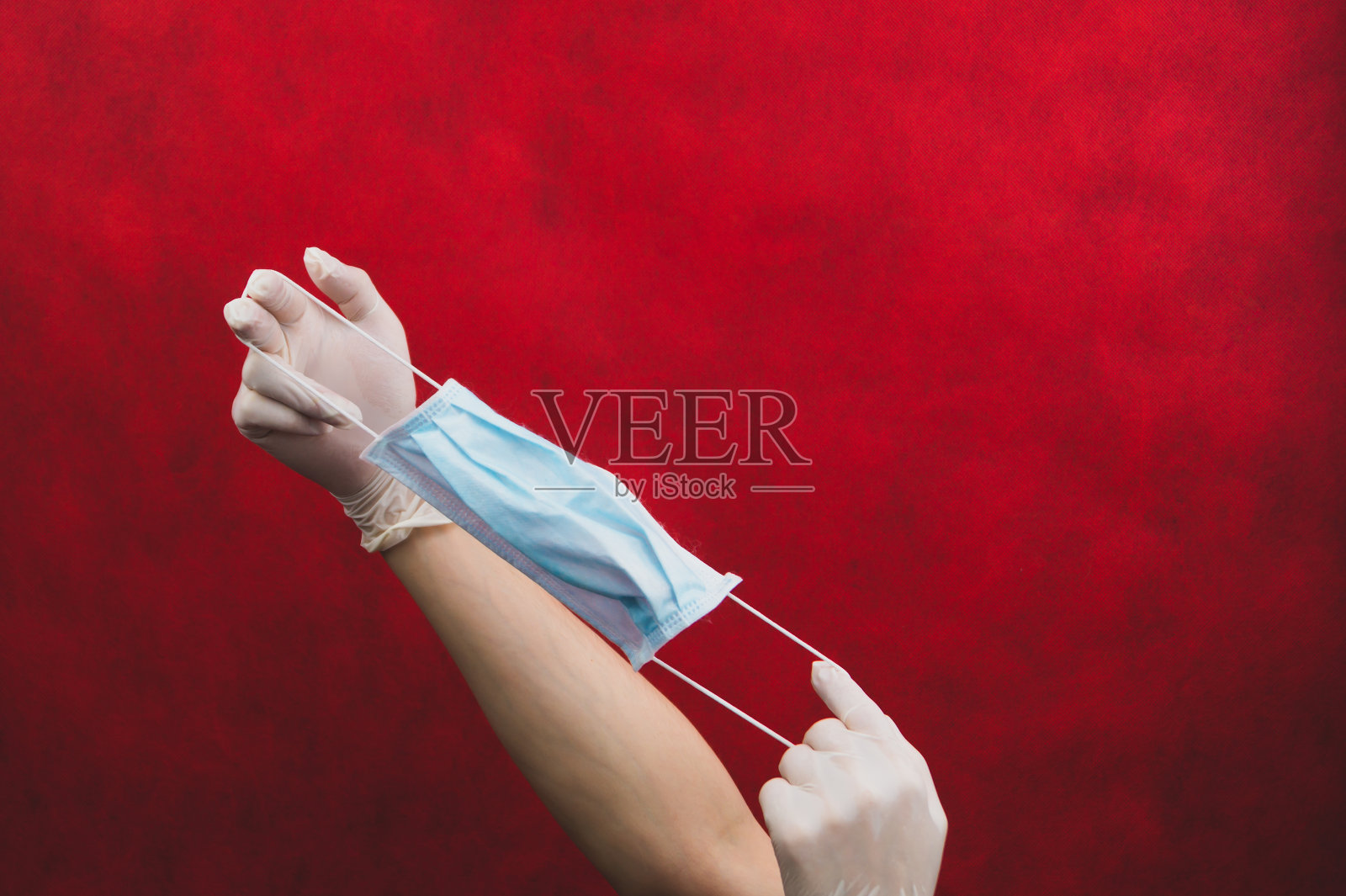 双手戴上防护手套,拉伸医用口罩。预防呼吸道疾病和病毒的措施。戴着白色外科手套的双手手持一次性口罩以保护身体照片摄影图片