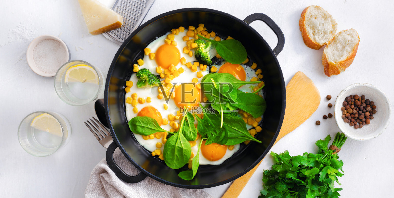 健康的早餐桌子与煎锅鸡蛋,菠菜在白色的背景俯视图照片摄影图片