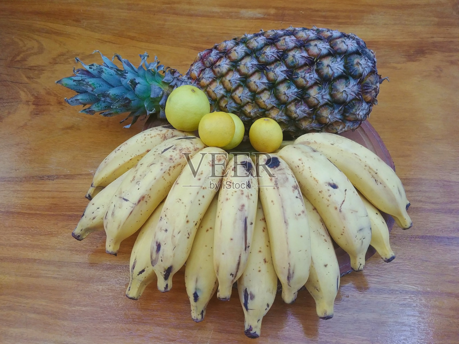 木桌上放着菠萝、香蕉和柠檬照片摄影图片