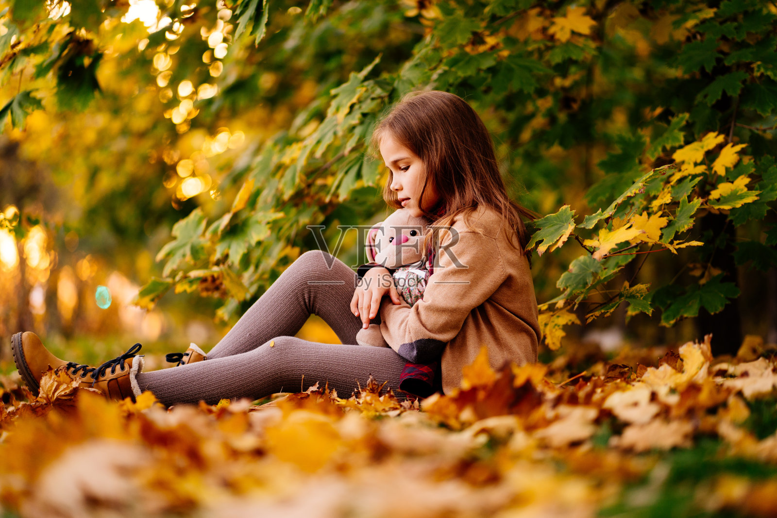 坐在落叶地上的悲伤小女孩,孩子们的怨恨照片摄影图片