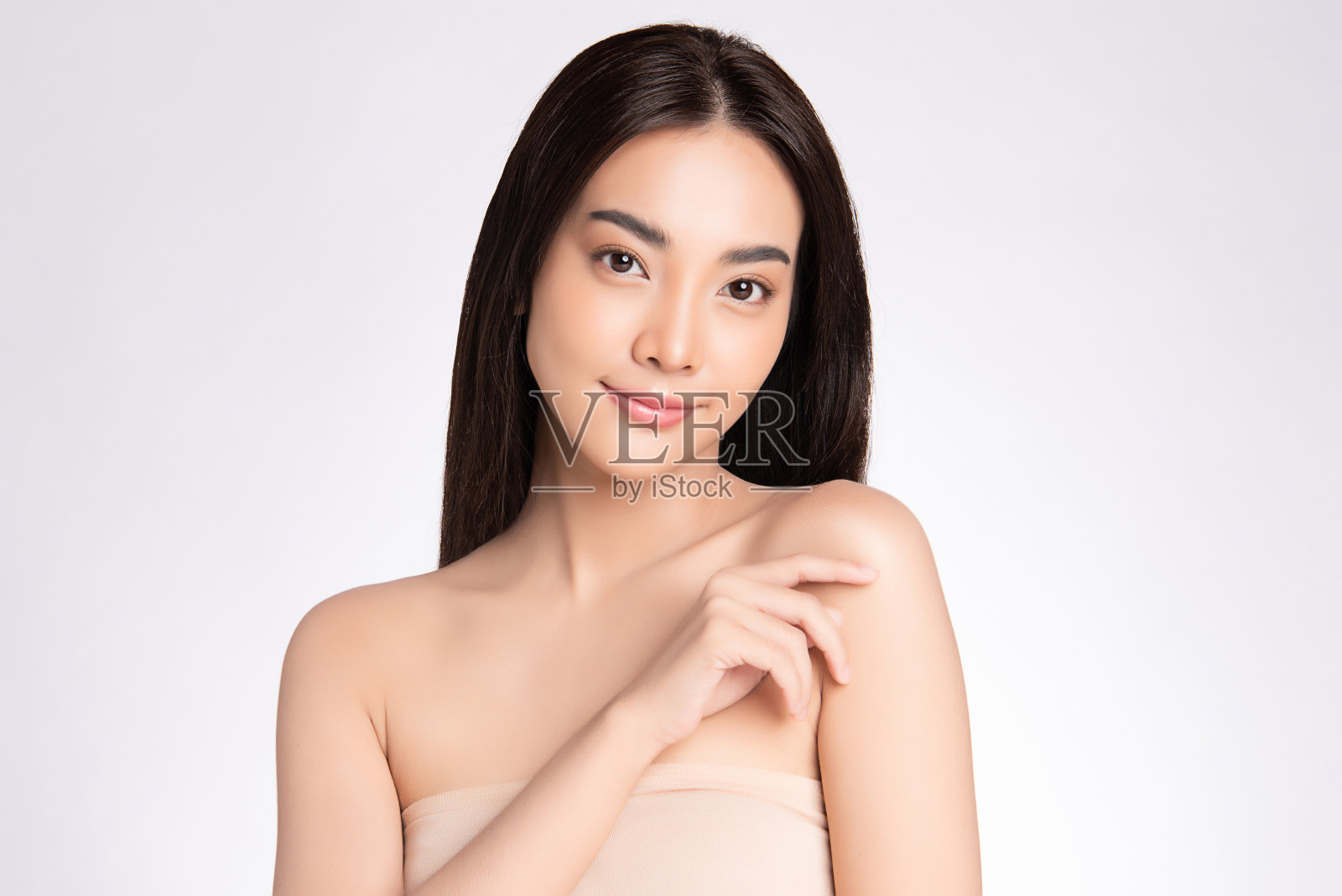 美丽的脸。微笑的亚洲妇女触摸健康的皮肤肖像。美丽快乐的女孩模型与新鲜的容光焕发的面部水润皮肤和自然的化妆在白色的背景,照片摄影图片