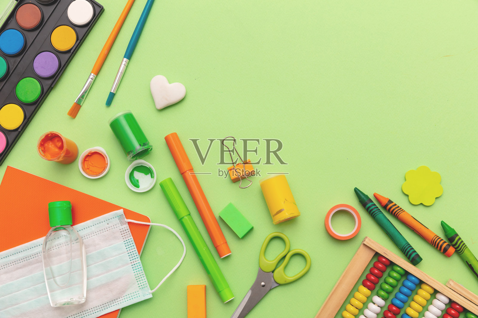 学校的冠状病毒传播预防措施。医用口罩、酒精消毒凝胶和粉彩绿色背景文具照片摄影图片