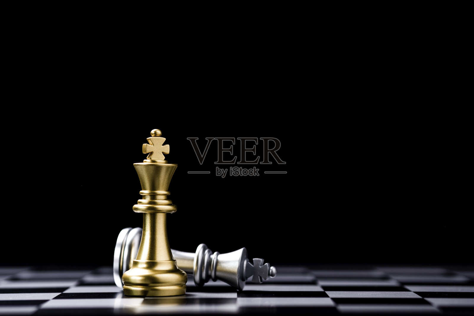 站在棋盘上的金王棋和倒下的银王棋。优胜者的商业竞争和营销策略策划理念。照片摄影图片