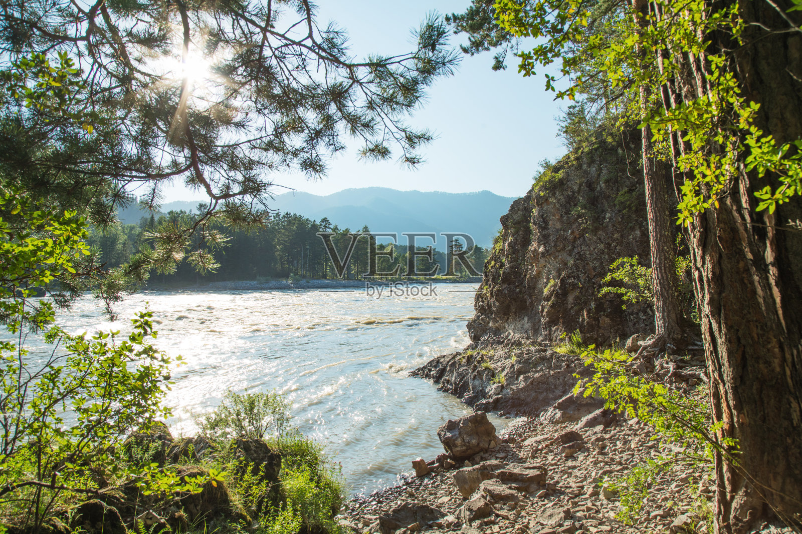 夏天的一天,山上的一条小河,阳光灿烂。岩石和树木,蓝天。照片摄影图片