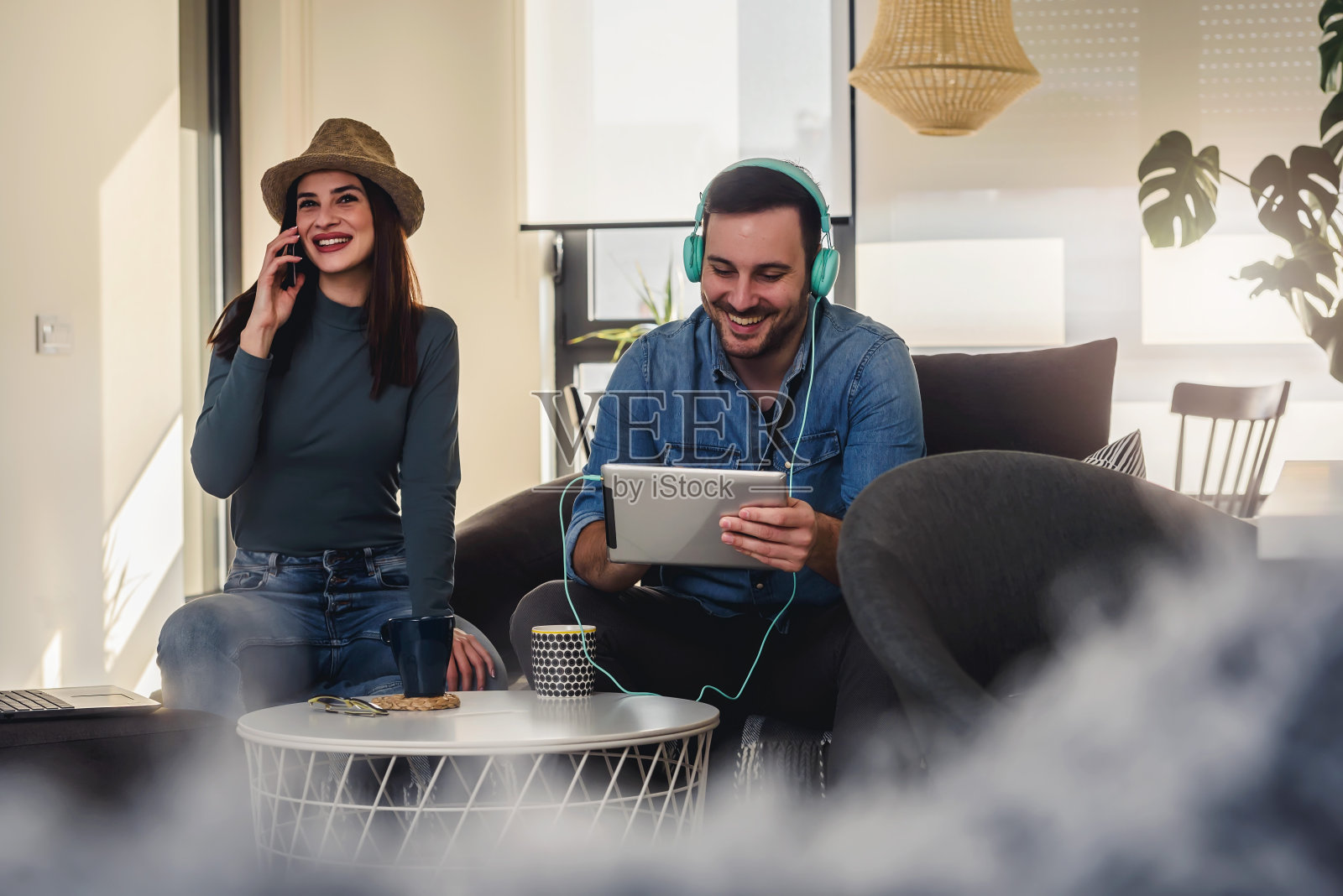 一对在家里用移动设备听音乐的帅气情侣照片摄影图片