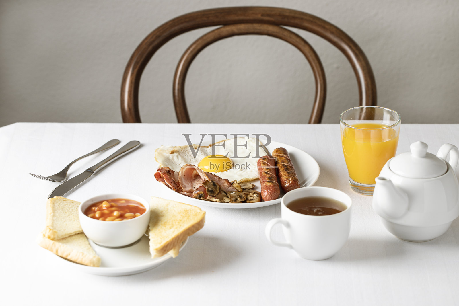餐桌上有英式早餐,煎蛋,香肠,培根,豆类,蘑菇,西红柿,吐司和茶。本空间照片摄影图片