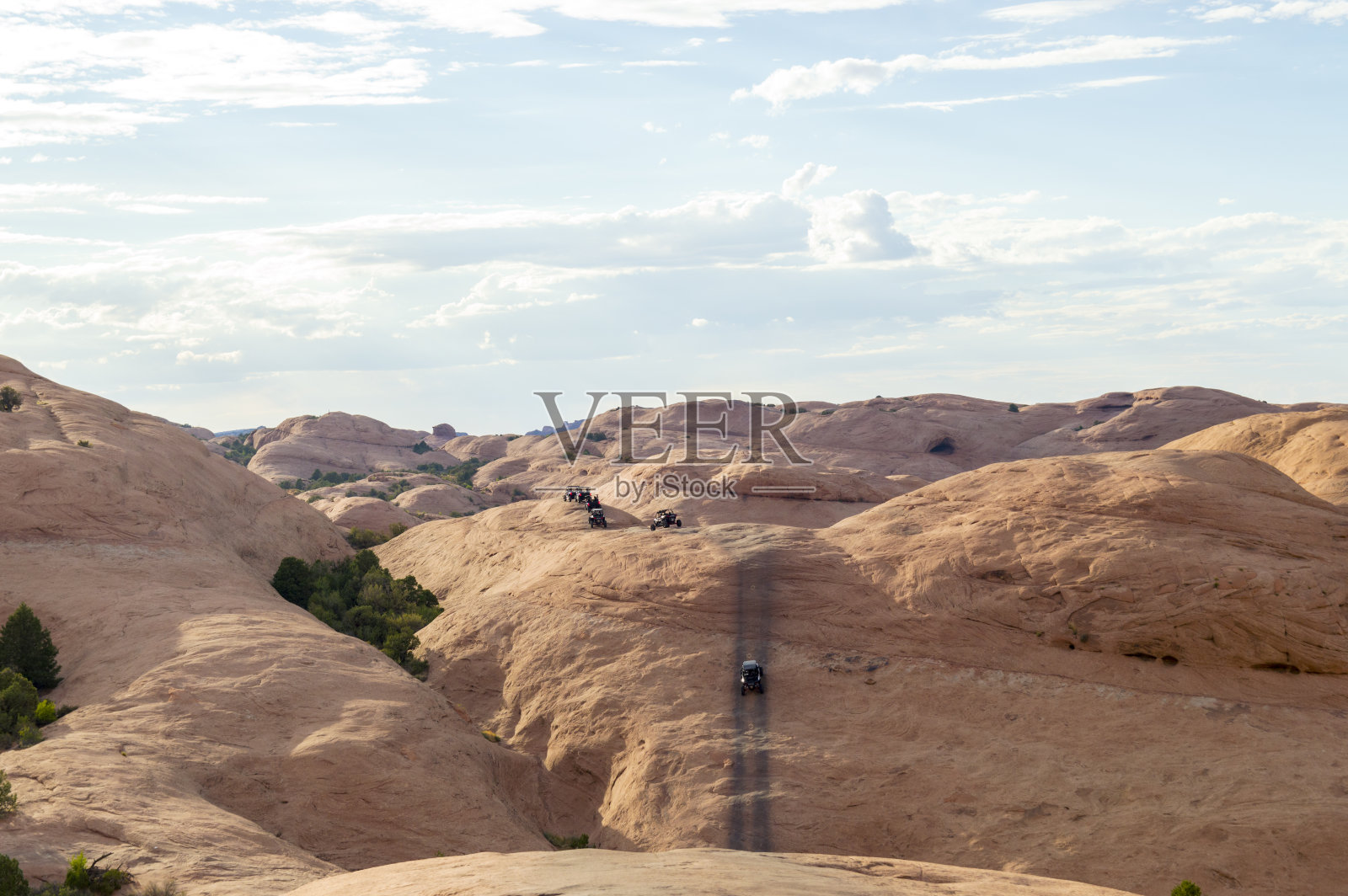 在犹他州摩押附近的地狱复仇地区,路边的车辆并排爬上砂岩山顶照片摄影图片