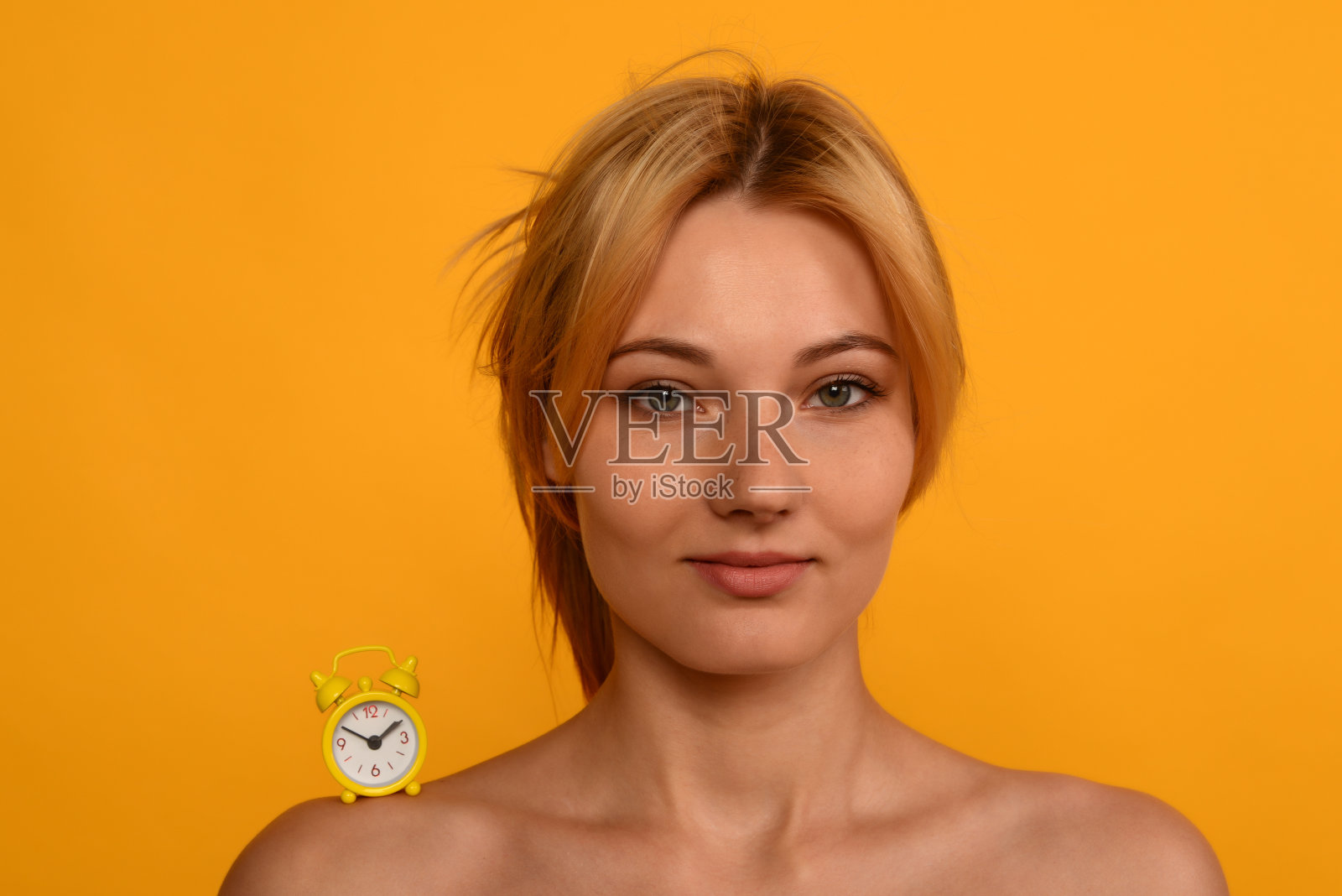 一个肩膀上有钟的年轻美丽的女孩的肖像。老化的概念。照片摄影图片